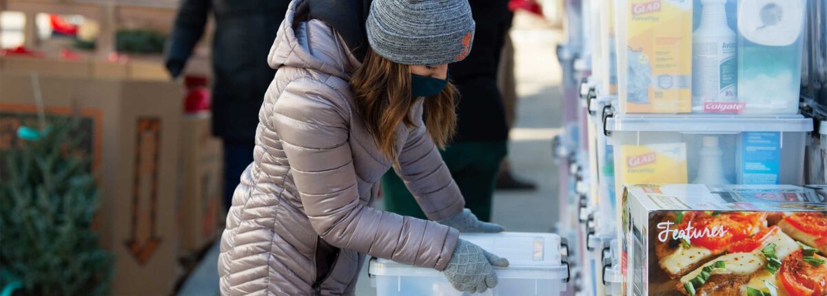 Volunteer packing boxes outside in a winter coat and hat