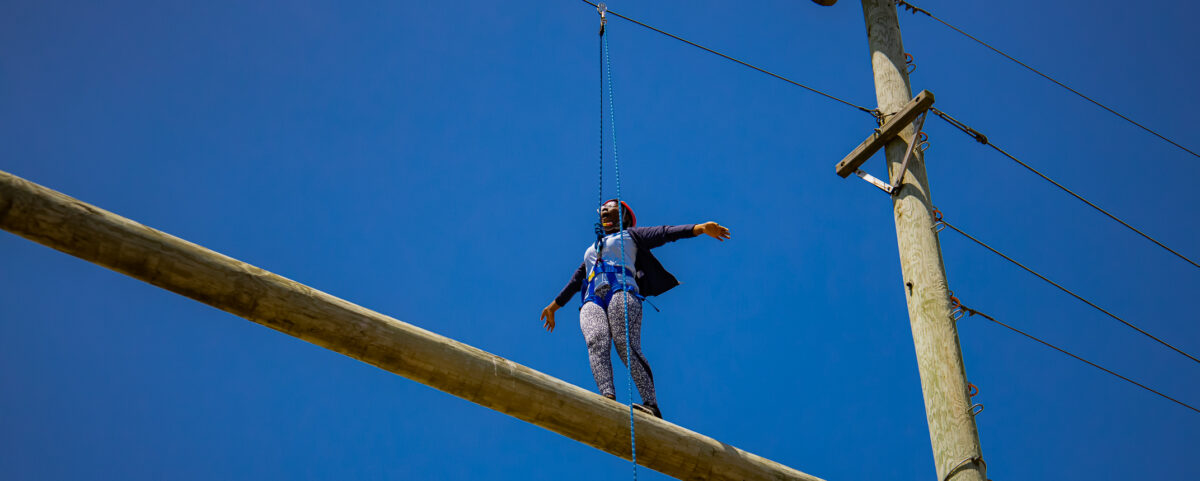 Camper walking across beam on high ropes