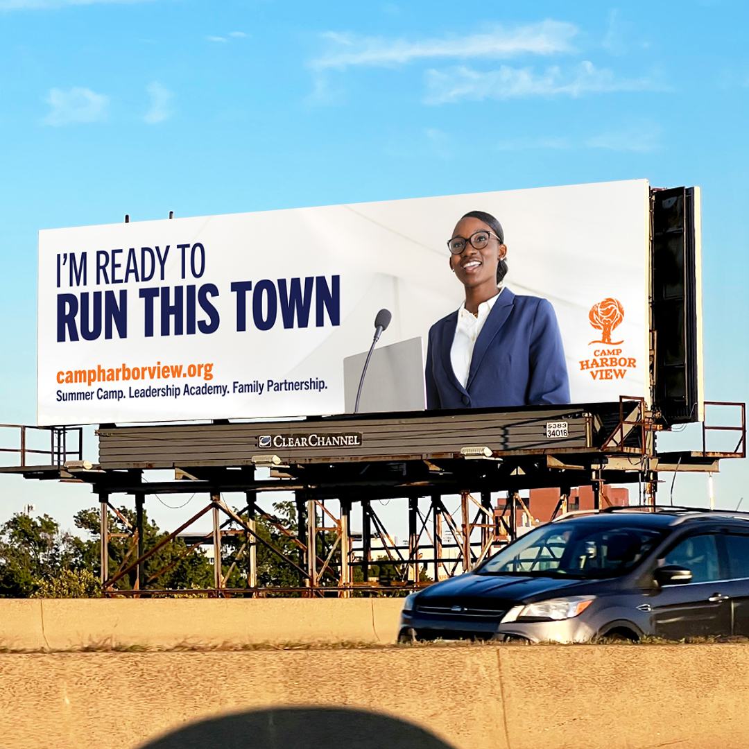 Photo of a Camp Harbor View billboard on route 93 in Boston that says "I'M READY TO RUN THIS TOWN" with an image of a teen speaking at a podium wearing a blazer.