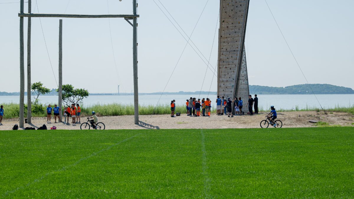 View of campers at the rock wall and campers riding bikes