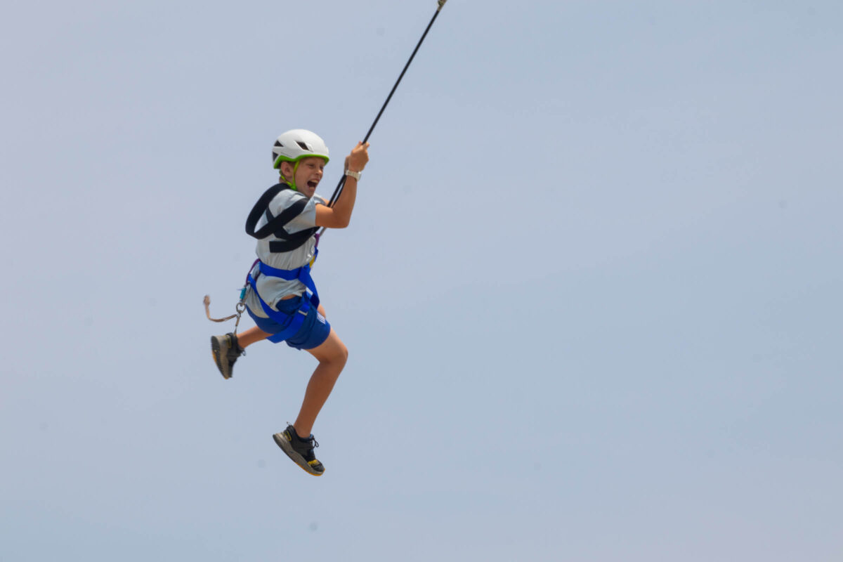A camper swinging in the air in a ropes course