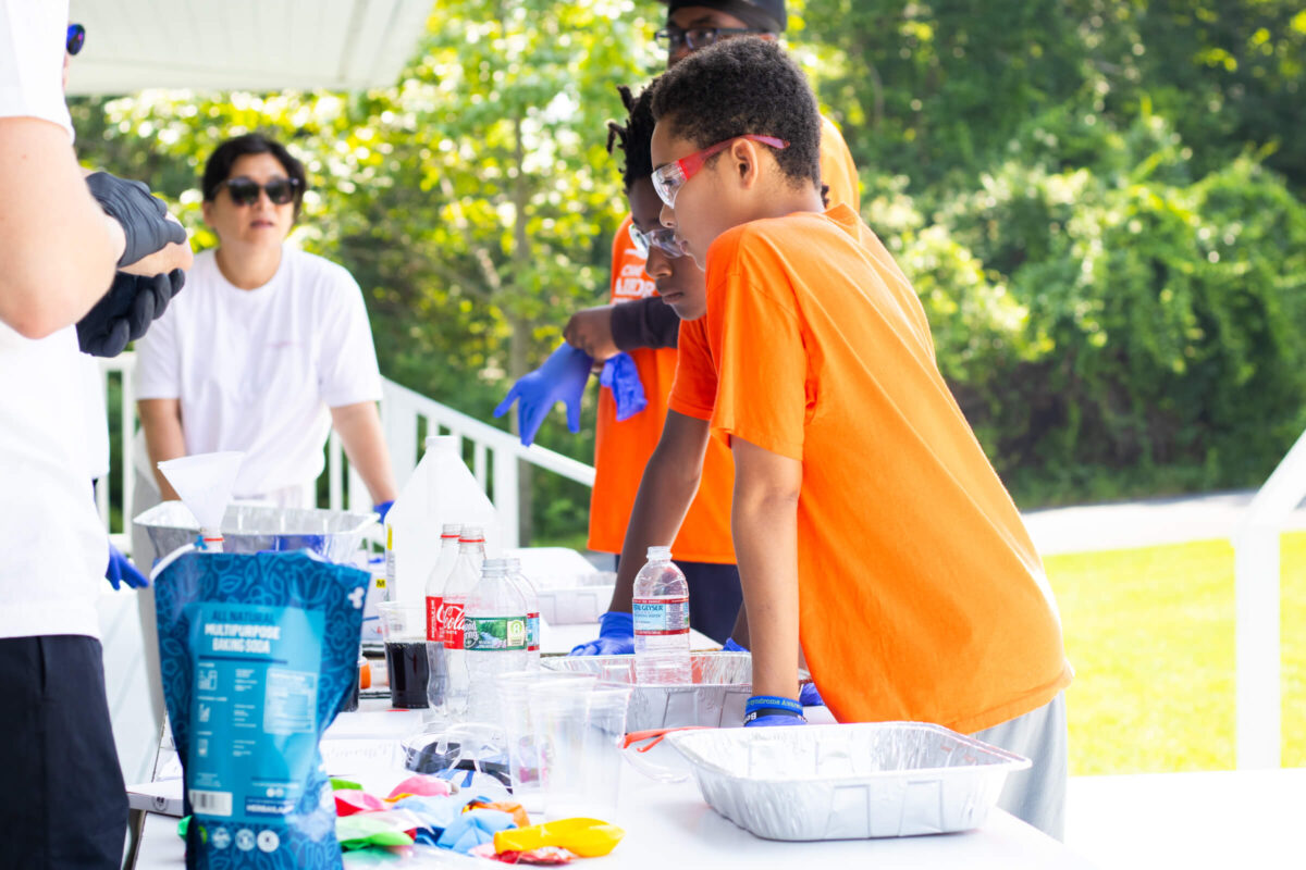 Campers do a science experiment with volunteers