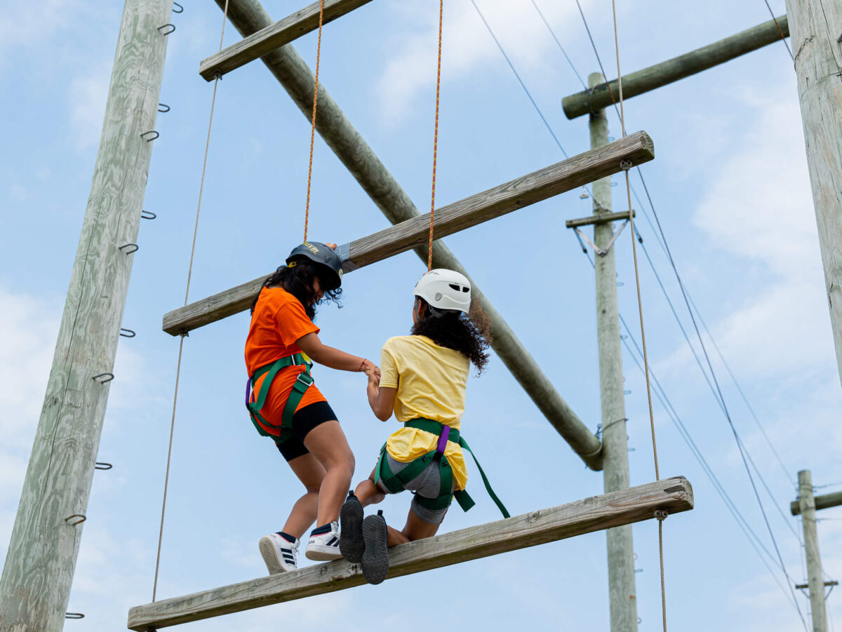 Camper helping another camper on ropes course