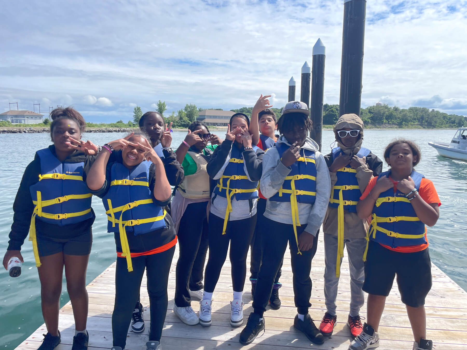 group of teens in life vests standing on the dock smiling