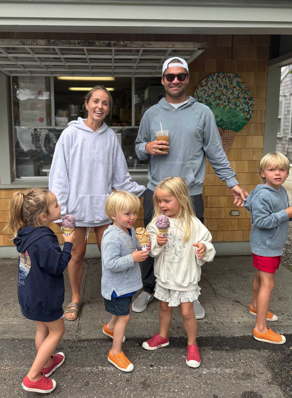Family standing outside an ice cream shop, smiling while children hold colorful ice cream cones.